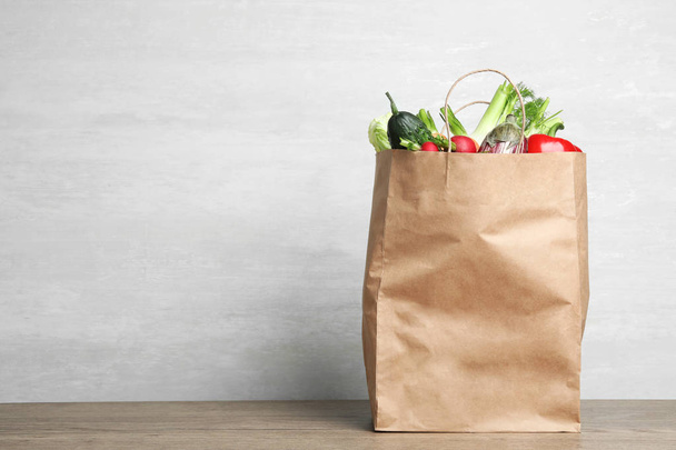 Paper bag with vegetables on table against grey background. Space for text - 写真・画像