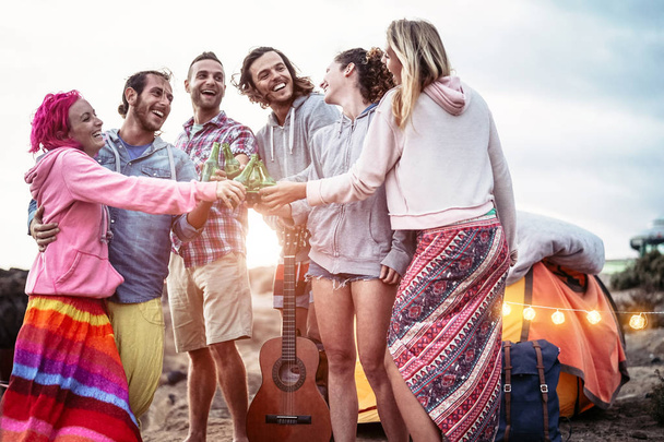 Счастливые друзья, поднимающие тосты за пиво на закате - Молодые люди, весело проводящие время в кемпинге под открытым небом - Millennial, summer, vacation, love and young holiday lifestyle concept
 - Фото, изображение