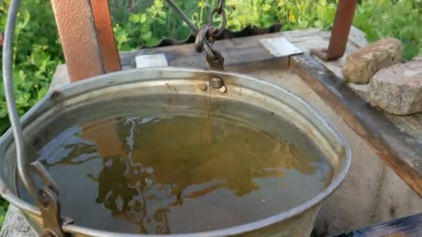 井戸の汚れた水惑星の生態学女性は水を引くために素朴な井戸にバケツでチェーンをドロップします. - 映像、動画
