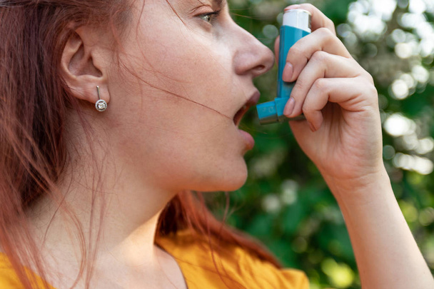 Medisch concept. Jonge vrouw met behulp van astma-inhalator - Foto, afbeelding