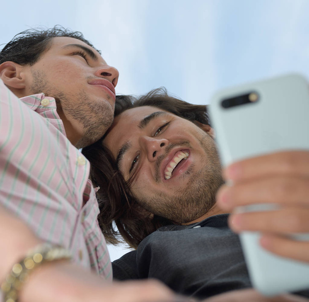 Feliz pareja gay disfrutando con el teléfono móvil
 - Foto, Imagen