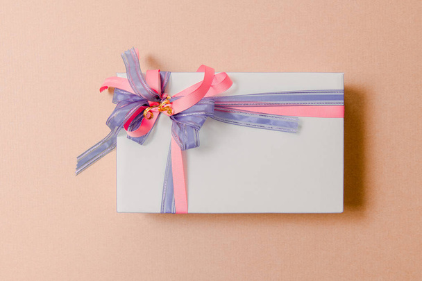 Luxury box tied with blue and pink ribbons on pink background - Photo, image