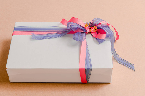 Luxusní box svázaný modrými a růžovými stuhami na růžovém pozadí - Fotografie, Obrázek