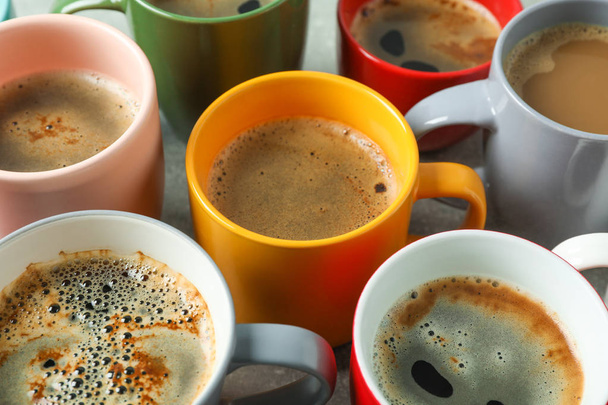 Veelkleurige kopjes koffie op grijze tafel als achtergrond, close-up - Foto, afbeelding