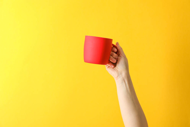 Женская рука держать красную чашку на фоне цвета, пространство для текс
 - Фото, изображение