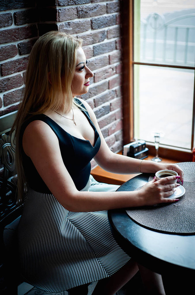 Stylish blonde woman sitting in cafe and drinking cup of coffee - Foto, Bild