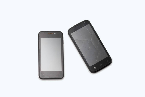Due telefoni neri si trovano su uno sfondo bianco. Lo smartphone rotto. Crepe sullo schermo
 - Foto, immagini
