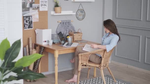 Genç kadın serbest yazar ev stüdyosunda dergi okuyor.. - Video, Çekim