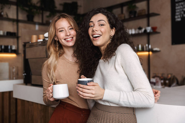Two cheerful young girls friends standing at the cafe - Foto, Bild