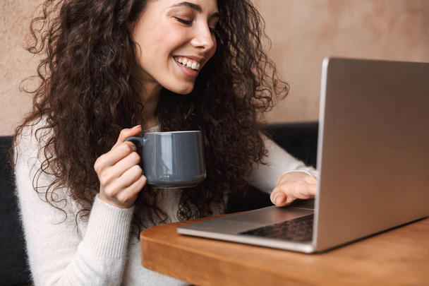 Mujer joven sonriente usando computadora portátil
 - Foto, Imagen