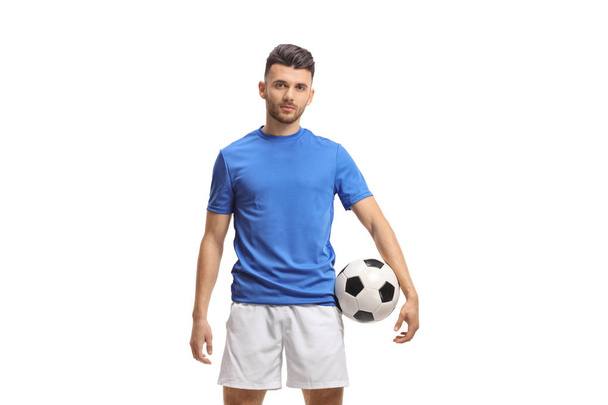 Soccer player holding a football and looking at the camera isolated on white background - Фото, изображение