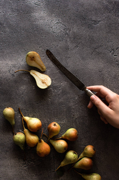 Hands Cutting Pears on Rustic Dark Background with Copy Space. Antioxidant Support. - Photo, Image
