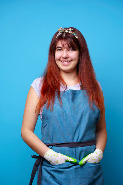 Photo of brunette in blue apron and gloves on blank background - Fotografie, Obrázek