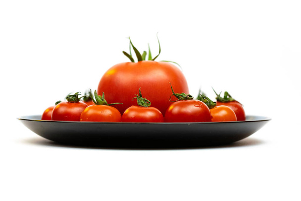 Tomatoes in a black plate isolated on white background. Composition of red tomatoes on a white background. Place for text - Photo, Image