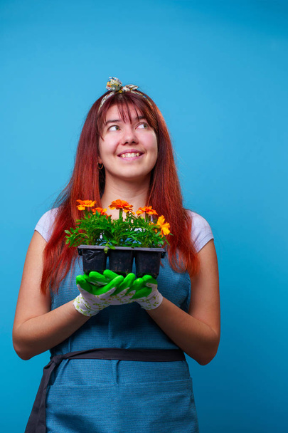 Photo of happy brunette looking up with marigolds in her hands - Foto, Imagen