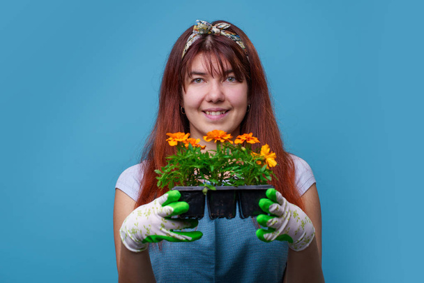 Picture of smiling brunette girl with marigolds in her hands - Foto, Imagen