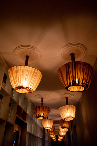 Rows of ceiling lamps with retro style lampshades draped with tulle covers. Interior perspective view. Lamp shades sewed from transparent brown tulle. Old-fashioned interior objects. Home decor items. Rustic style lighting. - Photo, Image