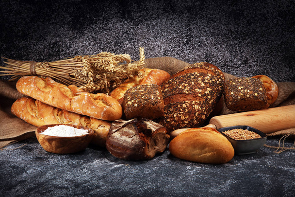 Assortiment van gebakken brood en broodjes op rustieke grijze bakkerij  - Foto, afbeelding