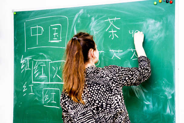 the teacher near the school board writes Chinese characters - 写真・画像