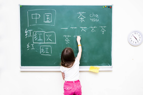 Дівчина біля шкільної ради пише китайські ієрогліфи - Фото, зображення