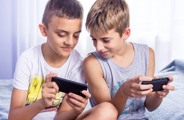 Cute little boys, brothers playing online games on their smart phones. - Fotografie, Obrázek