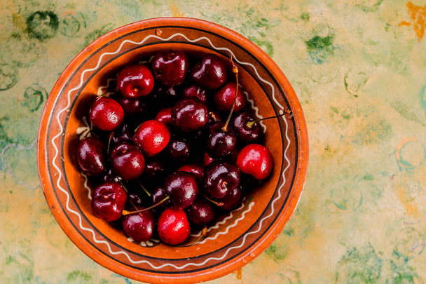 Bowl with fresh cherries on a wooden blue background. Ripe sweet cherries. Healthy food concept. Cherries in ceramic bowl.sweet cherries. Healthy food concept. Cherries in ceramic bowl. - Фото, изображение