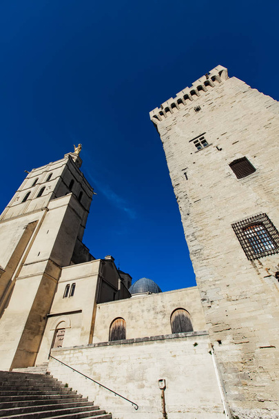 Avignon cathedral (Cathedral of Our Lady of Doms) next to Papal palace (Palais des Papes) under blue sky in Avignon, France - Photo, Image