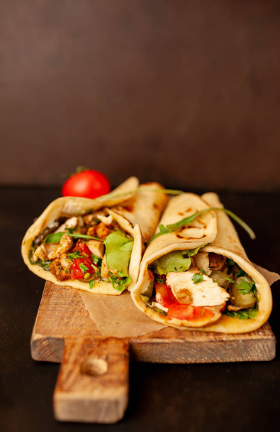 Traditional mexican tacos with salad on wooden chopping board over black concrete background - Foto, imagen