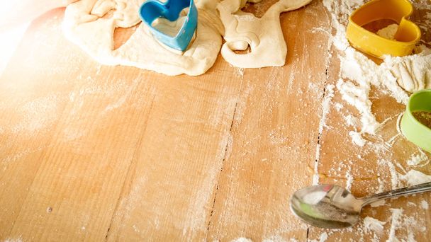 Vista de perto de alto ângulo na mesa de madeira coberta com farinha, massa, ferramentas de cozinha e ingredientes para cozinhar e assar na cozinha
 - Foto, Imagem
