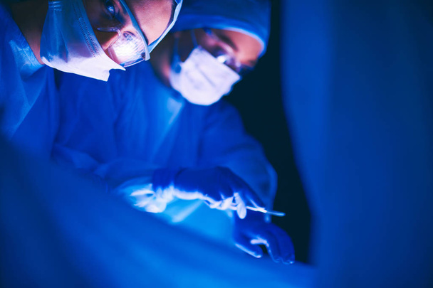 Doctors team in surgery in a dark background. - Fotó, kép