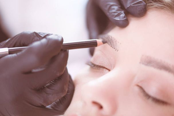 Cosmetólogo aplicando maquillaje permanente en las cejas - Foto, Imagen