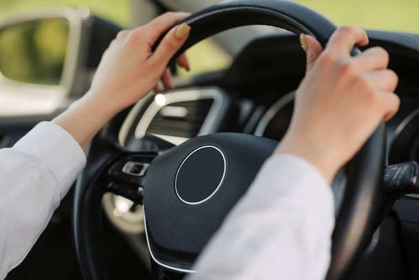 Las manos de la mujer sosteniendo el volante negro mientras conduce un coche
. - Foto, imagen