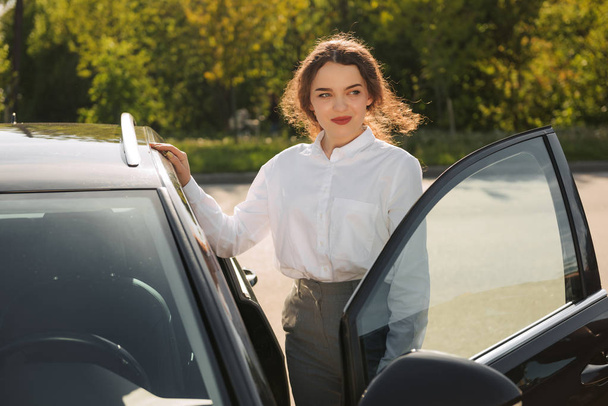 Business woman standing near her car with sunny weather outdoors. - Photo, image