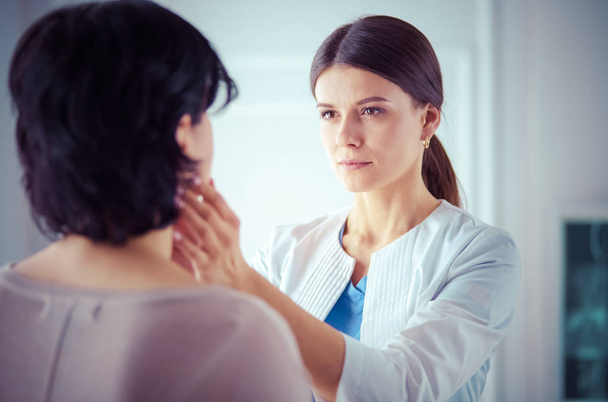 A serious female doctor examining a patients lymph nodes - Foto, Imagem