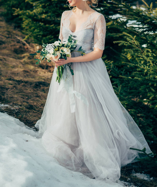 schöne brünette Braut in hellem Chiffon Brautkleid bestickt mit Perlen posieren in der Nähe der Berge - Foto, Bild