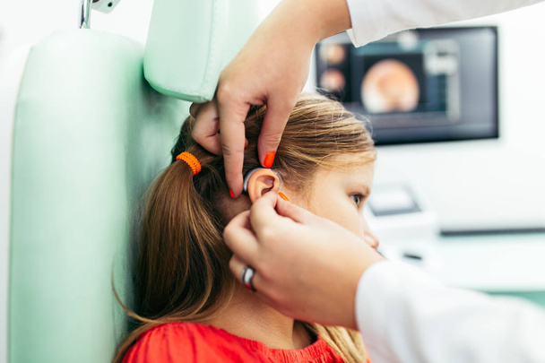 Young girl at medical examination or hearing aid checkup in otolaryngologist's office - 写真・画像