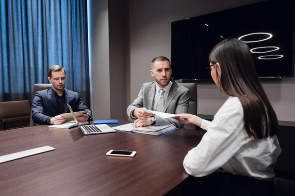 Démarrage d'entreprise, les gens d'affaires créatifs de différents âges et races se réunissent dans la salle de réunion dans l'intérieur de bureau moderne sombre, discuter activement
 - Photo, image