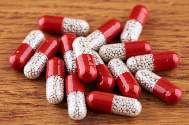 Muchas píldoras blancas y rojas sobre fondo de madera
 - Foto, Imagen