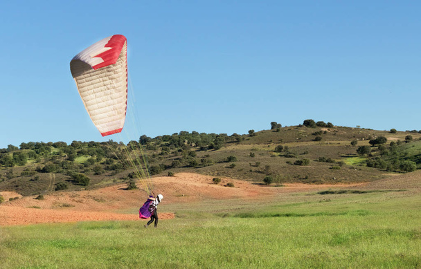 Aterragem piloto fêmea com um parapente
 - Foto, Imagem