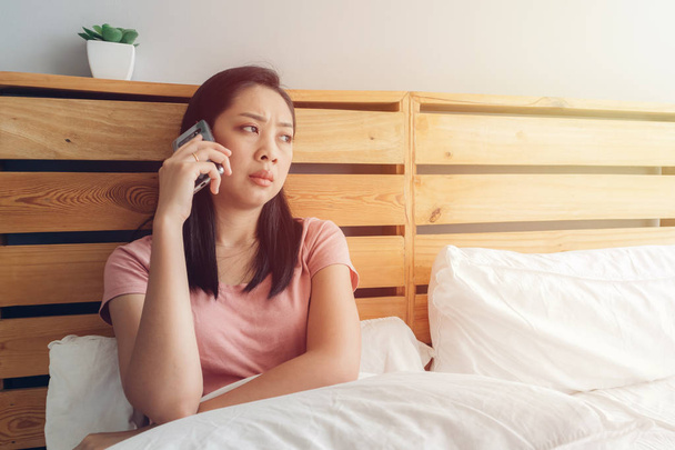 Upset woman is having a phone conversation on her bed. - Fotoğraf, Görsel