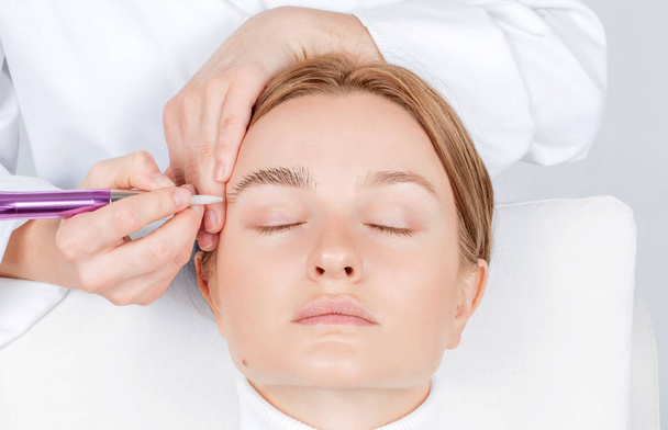 Microblading eyebrows. Attractive woman getting facial care and permanent makeup.  - 写真・画像