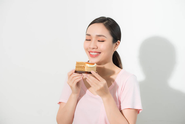 Mooie lachende Aziatische jonge vrouw met een chocoladecake geïsoleerd op witte achtergrond. - Foto, afbeelding