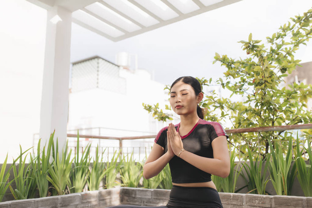 Beautiful woman doing yoga outdoors on a rooftop terrace - Photo, Image
