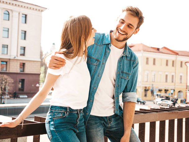 Portrait of smiling beautiful girl and her handsome boyfriend. Woman in casual summer jeans clothes. Happy cheerful family. Female having fun on the street background.Looking at each other - Fotó, kép