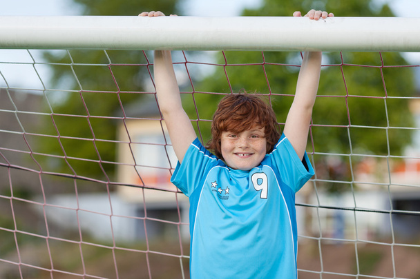strong boy hanging on soccer goal - Foto, afbeelding