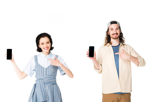young couple holding smartphones in hands and pointing with fingers at phones isolated on white - Photo, Image