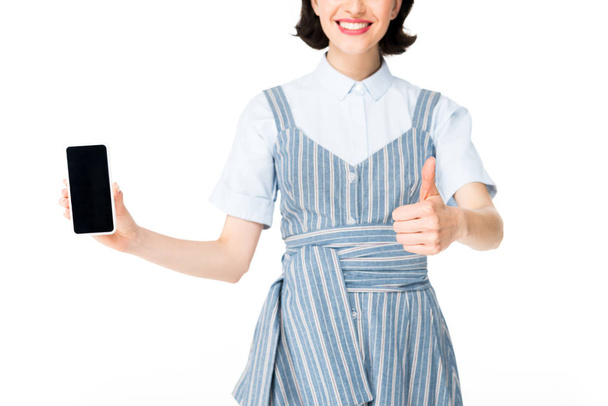 oříznutý pohled dívky držící smartphone v ruce a ukazující palec na bílou - Fotografie, Obrázek