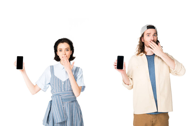 surprised young man and girl holding smartphones in hands isolated on white - Zdjęcie, obraz
