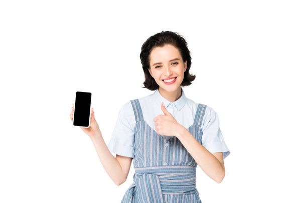 дівчина тримає смартфон в руці, посміхається і показує великий палець на камеру ізольовано на білому
 - Фото, зображення