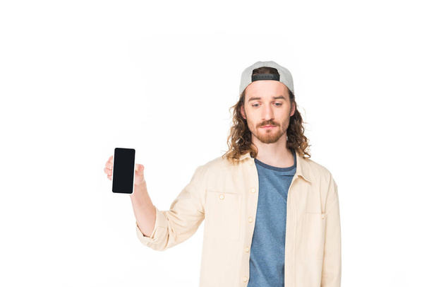 verdrietig jonge man met smartphone in handen en op zoek naar beneden geïsoleerd op wit - Foto, afbeelding